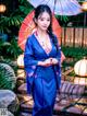 A woman in a blue kimono holding an umbrella.