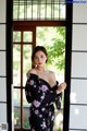 A woman in a black kimono standing in front of a window.