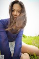 A woman in a blue shirt and white shorts sitting in the grass.