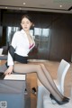 A woman sitting on top of a white chair next to a table.