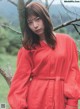 A woman in a red dress standing next to a tree.