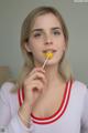 A young woman holding a lollipop in her mouth.