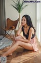 A woman sitting on the floor next to a plant.