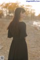 A woman in a black dress standing in a field.