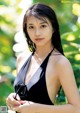 A woman in a black bathing suit posing for a picture.