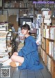 A woman sitting on the floor in front of a pile of books.