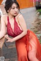 A woman in a red dress sitting on a bench.