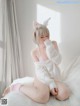 A woman in a bunny costume sitting on a bed.