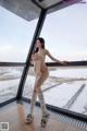 A naked woman standing in front of a window in the snow.