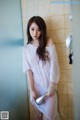 A woman standing in a bathroom holding a shower head.