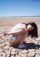 A woman kneeling on the ground in the middle of a dry lake.