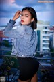 A woman in a denim jacket and black shorts posing for a picture.